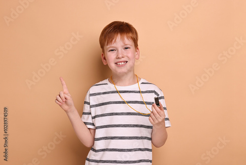 Little boy with whistle on beige background