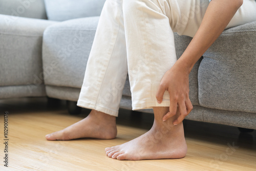 Foot pain, ache asian young woman hand scratch feet, itch foot, problem itchy skin on carpet at home, dermatitis from fungus, fungal bacterial infection, allergic reaction, eczema. Foot care concept. photo