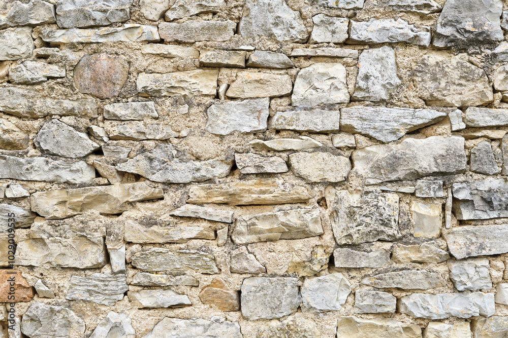 Obraz premium Background of a natural stone or sandstone masonry wall in South France. Detailed stone texture image in beige, brown, grey and green 