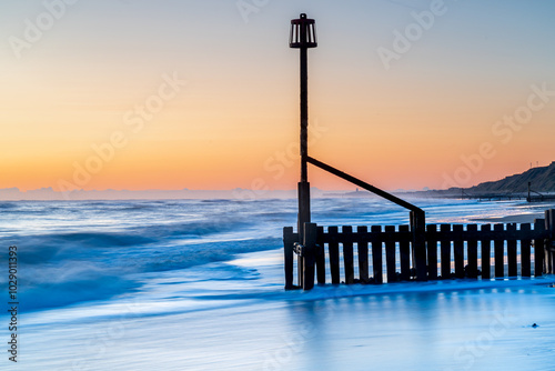 A beach groyne on the beach in Mundesley, Norfolk, UK before the sun was rising with a long exposure smoothing the water photo