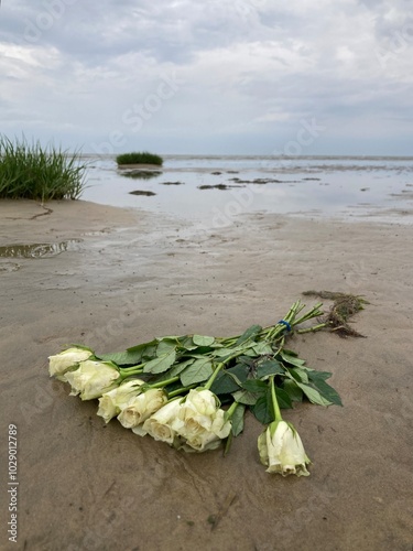 Weiße Rosen im Blumenstrauss nach Seebestattung im niedersächsischen Wattenmeer der Nordsee vor Cuxhaven