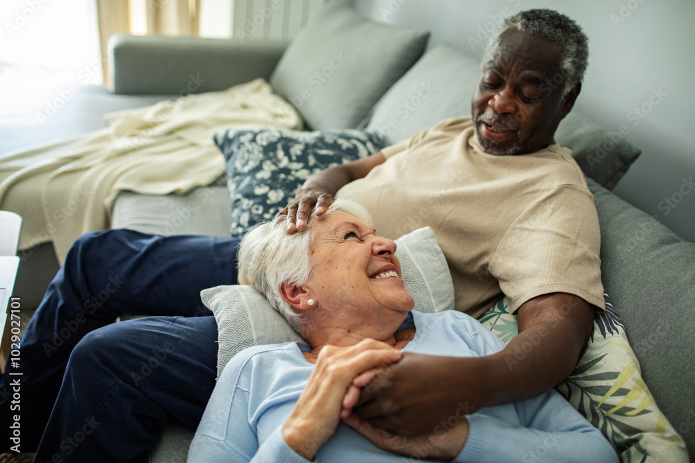 Happy senior couple relaxing together on couch at home Happy senior couple relaxing together on couch at home