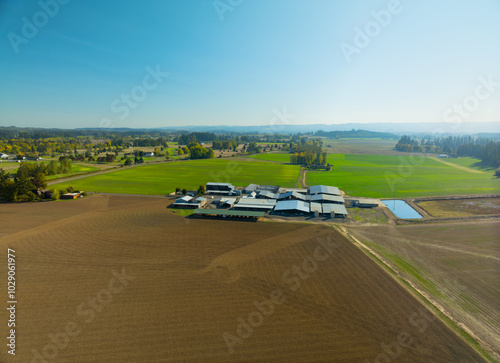 A large farm with a barn and a few houses in the background