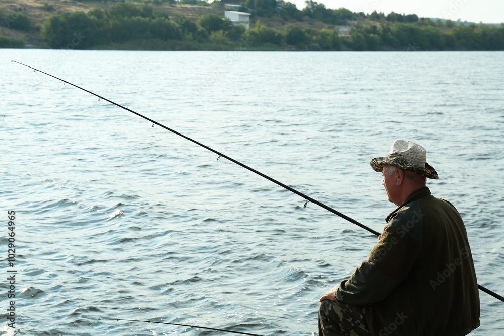 Fisherman with rod fishing near lake at summer Fisherman with rod fishing near lake at summer