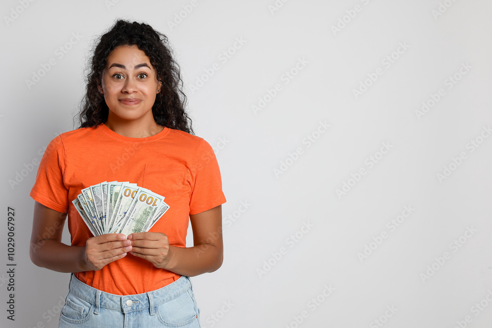 Smiling woman with dollar banknotes on light grey background, space for text Smiling woman with dollar banknotes on light grey background, space for text