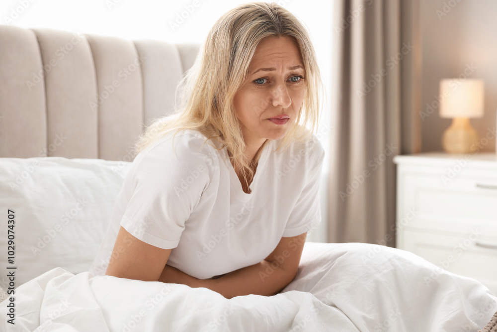 Menopause. Woman suffering from abdominal pain in bed at home Menopause. Woman suffering from abdominal pain in bed at home