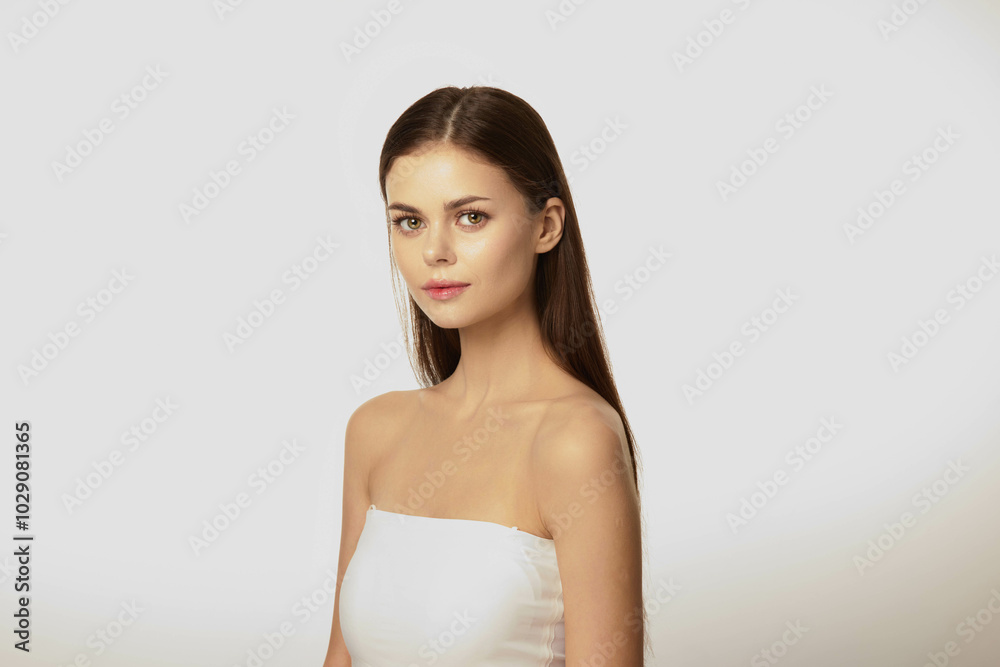 Beautiful young woman in white strapless dress standing with hands on hips, smiling and looking off to the side Beautiful young woman in white strapless dress standing with hands on hips, smiling and looking off to the side