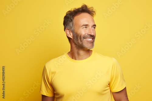 Portrait of a blissful man in his 40s sporting a breathable mesh jersey while standing against pastel yellow background