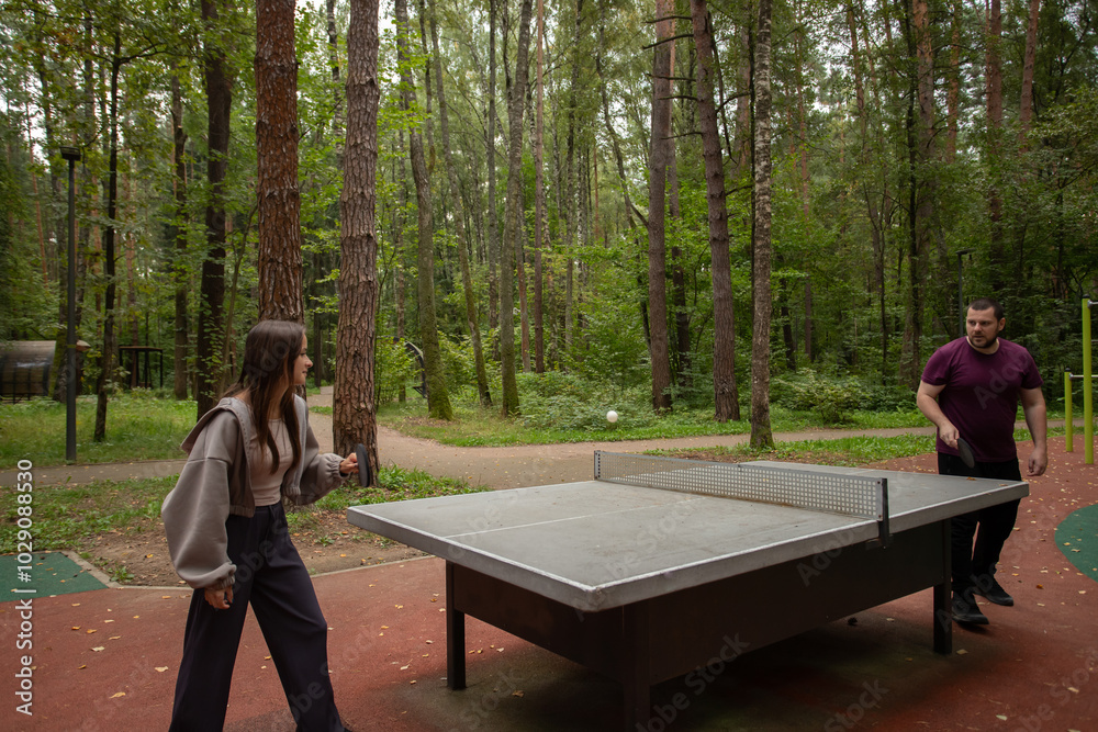 Fototapeta premium Ping pong players playing table tennis, woman and man in action, outdoor fitness and leisure.