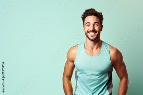 Portrait of a joyful man in his 20s wearing a lightweight running vest over pastel teal background photo