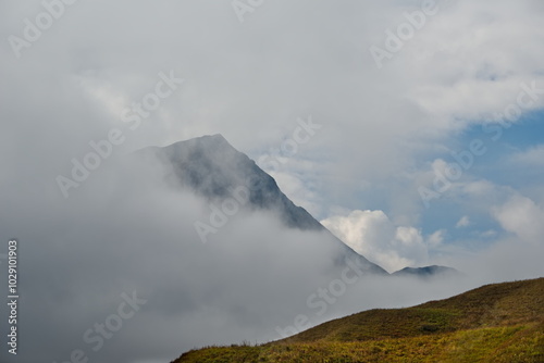 Russia. The Elbrus region. The high mountain peaks of the North Caucasus are surrounded by morning misty clouds hovering at different levels of inaccessible rocks. photo