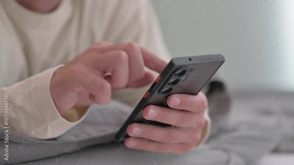 Male Hand Using Phone while Lying on Stomach in Bed Male Hand Using Phone while Lying on Stomach in Bed