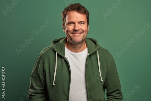 Portrait of a happy man in his 40s wearing a zip-up fleece hoodie on soft green background