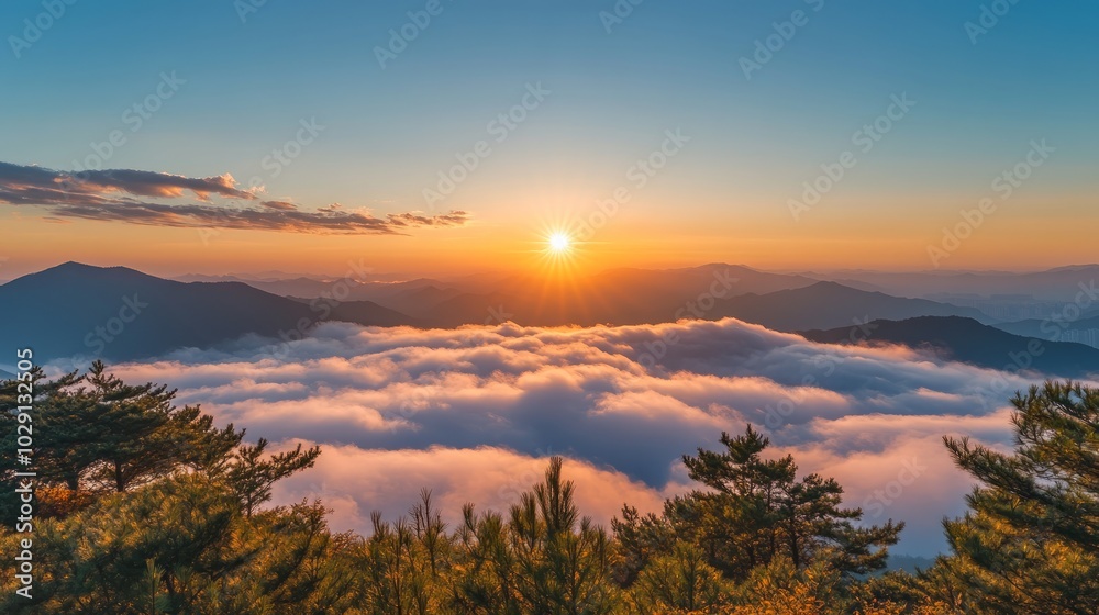 Obraz premium A stunning sunrise over a sea of clouds with a mountain range in the background, creating a picturesque and peaceful scene.