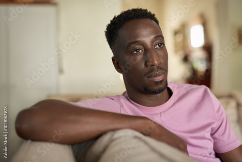 Young African man sitting at home looking deep in thought