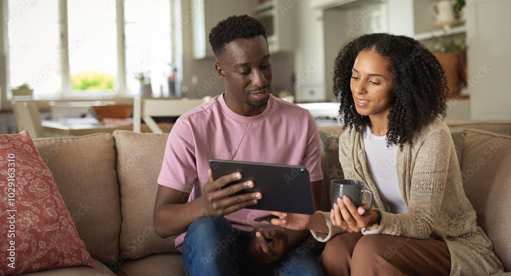 Smiling young multiracial couple using a digital tablet on a sofa Smiling young multiracial couple using a digital tablet on a sofa