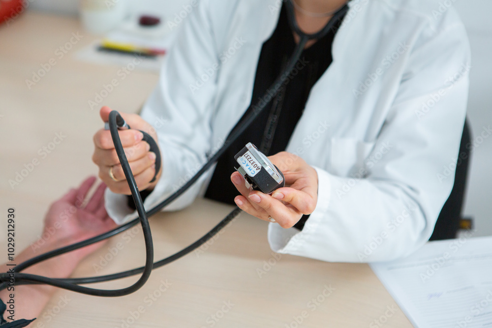 Fototapeta premium Close up of a female doctor sitting at the desk in the office. Doctor measuring blood pressure of patient in hospital. Medical and healthcare concept. 