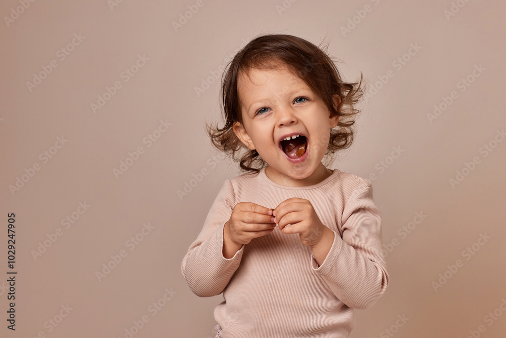 smiling child girl holding fruit pastille on beige background. healthy baby food. smiling child girl holding fruit pastille on beige background. healthy baby food.