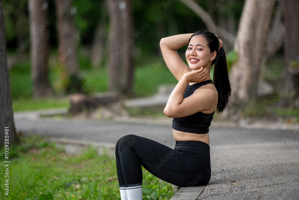 A woman is sitting on the grass with her legs crossed and her arms raised A woman is sitting on the grass with her legs crossed and her arms raised