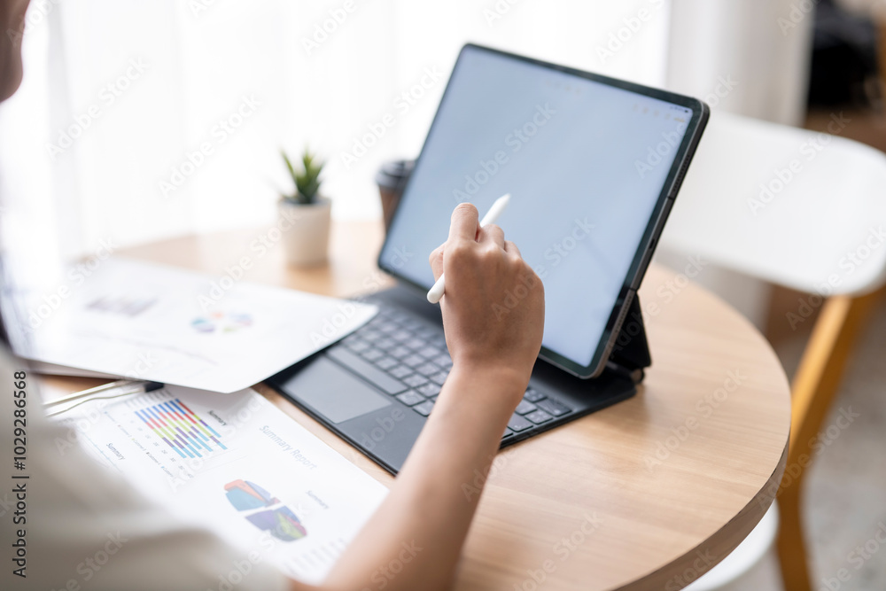 Businesswoman analyzing financial data on digital tablet and working with financial graphs at home office