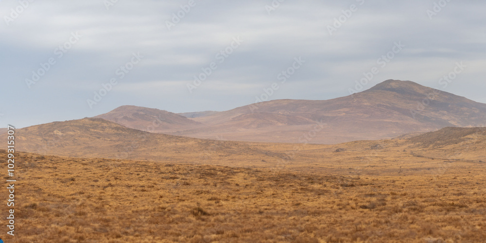 Vast mountainous desert landscape under cloudy sky Vast mountainous desert landscape under cloudy sky