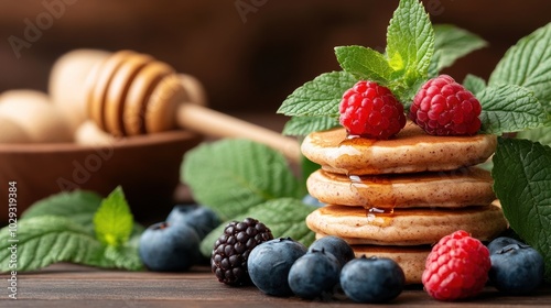 Stack of pancakes topped with fresh berries and mint on a wooden table. photo