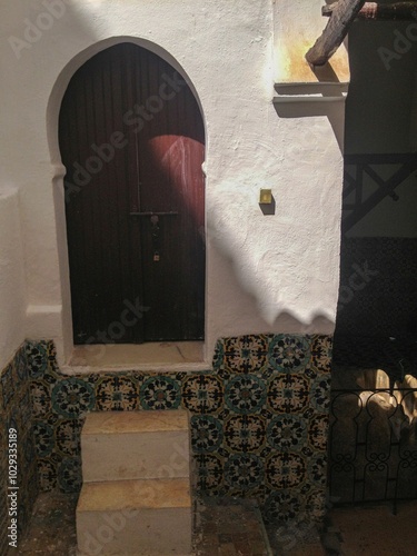 Inside view of the Sidi Boumediene mosque with its wooden doors, arcades and its green and ancient tiles and its Andalusian mosaic style ceramics. Tlemcen, Algeria photo