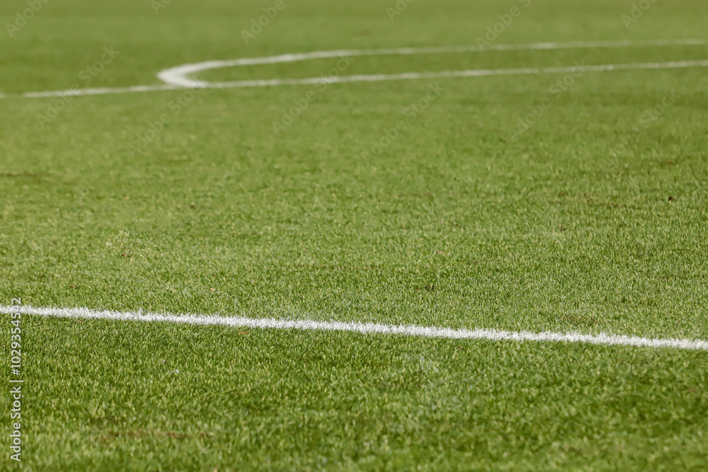 Obraz premium Football field with synthetic grass, with an angle below, highlighting the green of the lawn and some white lines.