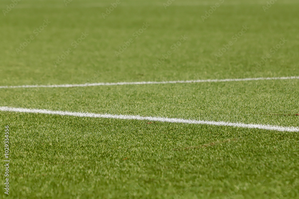 Obraz premium Football field with synthetic grass, with an angle below, highlighting the green of the lawn and some white lines.