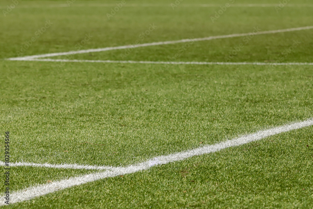 Obraz premium Football field with synthetic grass, with an angle below, highlighting the green of the lawn and some white lines.