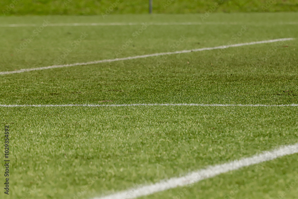 Obraz premium Football field with synthetic grass, with an angle below, highlighting the green of the lawn and some white lines.