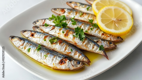 Grilled sardines garnished with fresh herbs and served with lemon slices on a white plate, showcasing a simple and flavorful seafood dish.