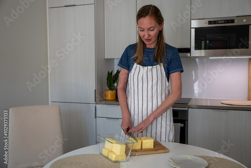 Young woman cutting butter in the kitchen at home. Healthy eating concept