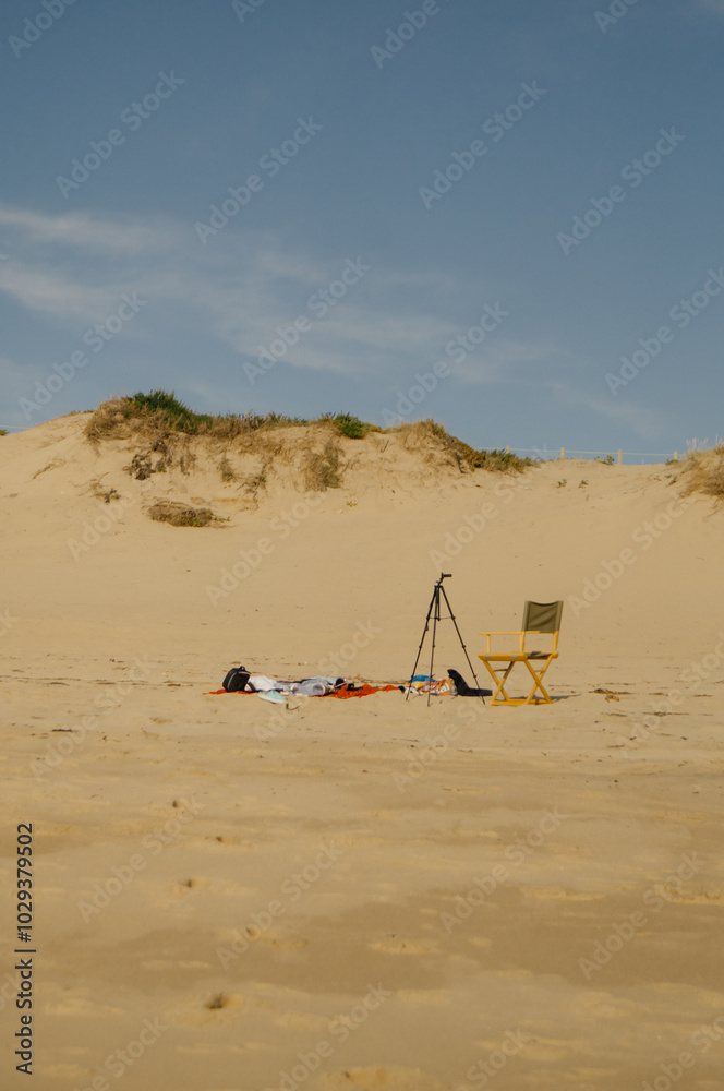 Beach scene with a tripod and chair set on the sand Beach scene with a tripod and chair set on the sand