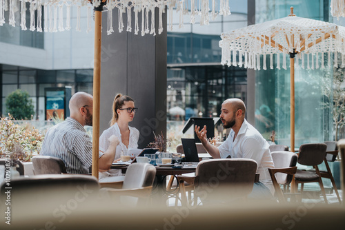 Startup team in a business meeting discussing, brainstorming, analyzing, and strategizing in a modern outdoor cafe setting. photo