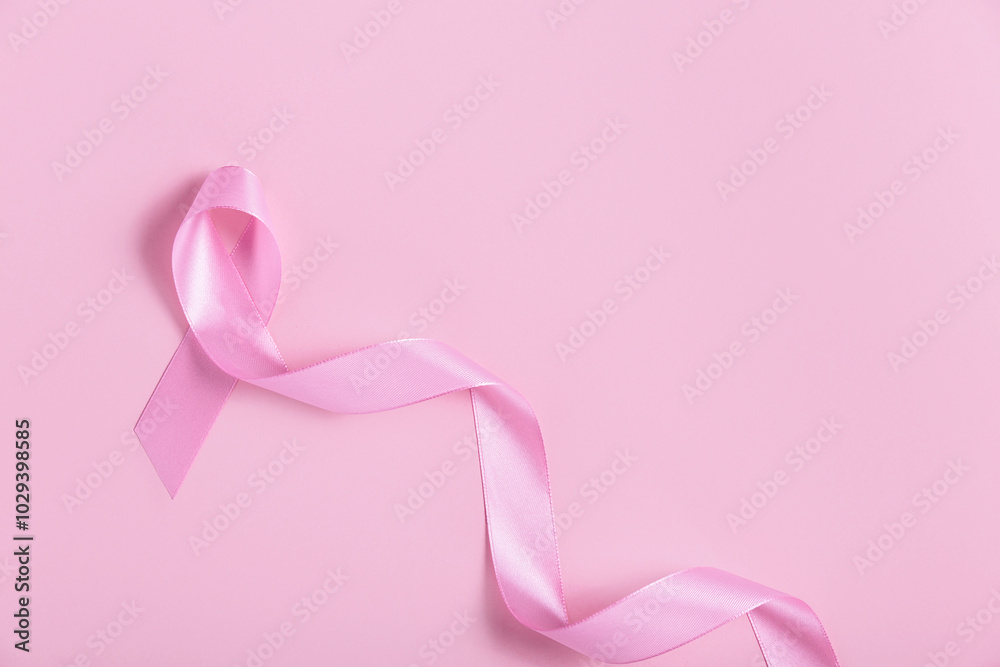 A pink ribbon lies on a matching pink background, symbolizing breast cancer awareness. The monochromatic design creates a soft, supportive visual for healthcare campaigns. A pink ribbon lies on a matching pink background, symbolizing breast cancer awareness. The monochromatic design creates a soft, supportive visual for healthcare campaigns.