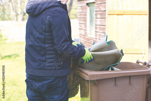A man puts rubbish into a brown bin