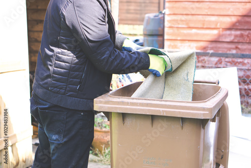 A man puts rubbish into a brown bin