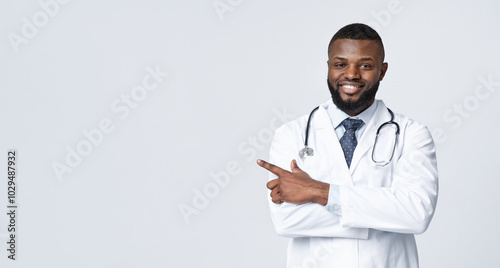 Note it, space for advertisement. Friendly black doc with arms crossed pointing at empty space over white background, panorama