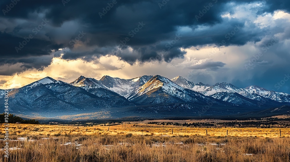 A mountain range shrouded in clouds with foreground mountains and a field of green grass A mountain range shrouded in clouds with foreground mountains and a field of green grass