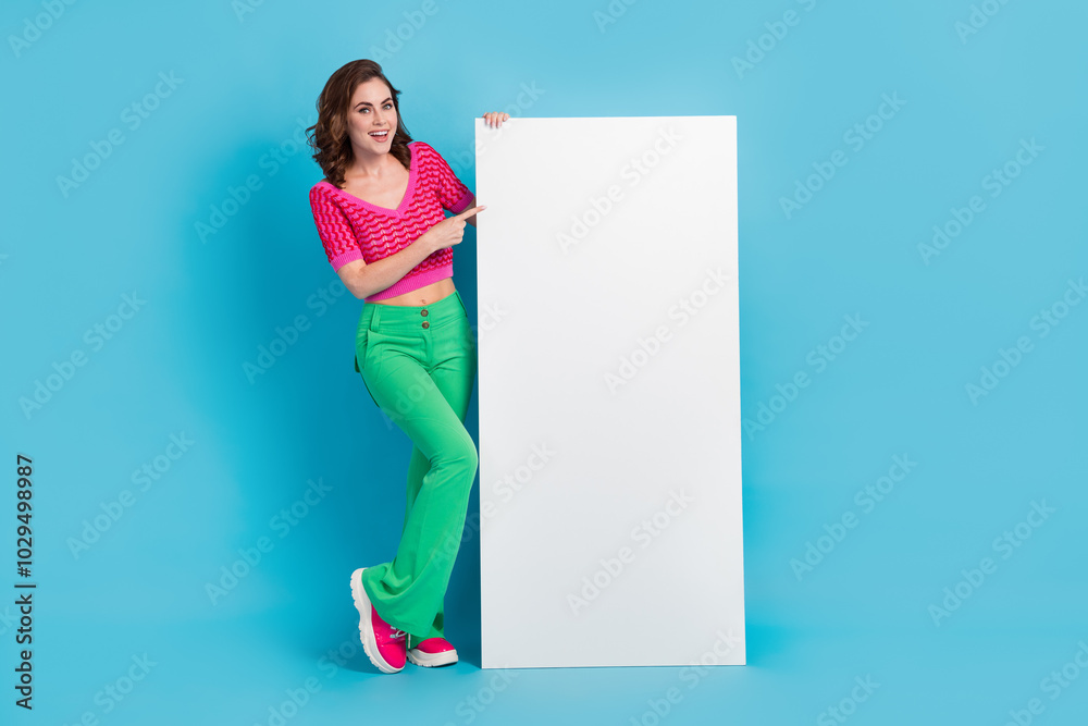 Full length photo of pretty cute lady wear pink retro clothes presenting empty space modern device isolated on blue color background Full length photo of pretty cute lady wear pink retro clothes presenting empty space modern device isolated on blue color background