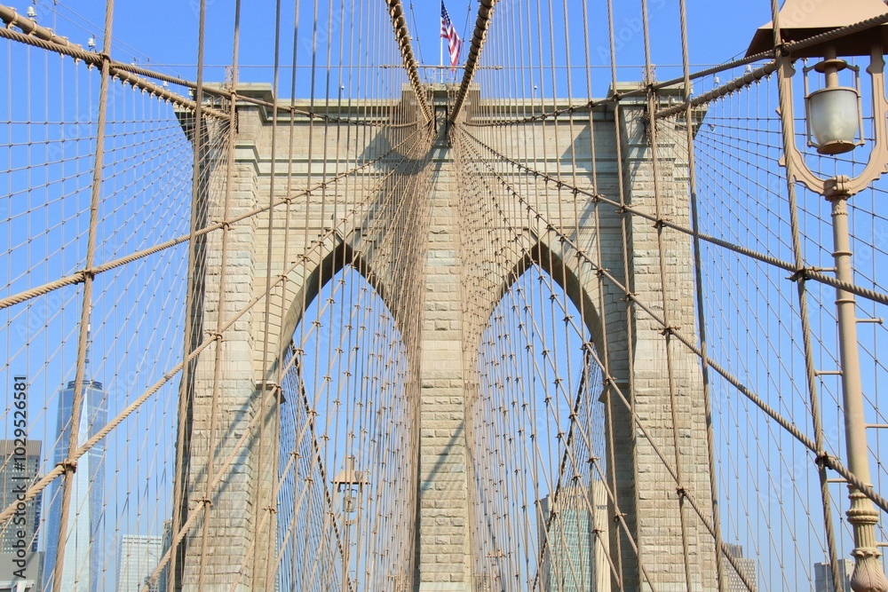 Fototapeta premium Brooklyn Bridge cables and tower under a clear blue sky.