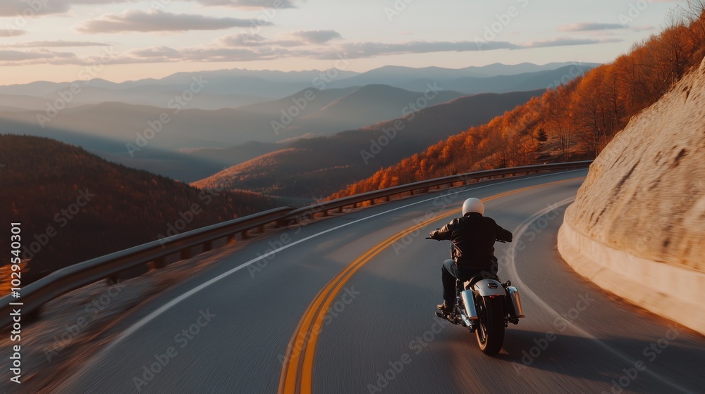 A motorcyclist enjoying a scenic ride through winding mountain roads during autumn's golden hour in the countryside A motorcyclist enjoying a scenic ride through winding mountain roads during autumn's golden hour in the countryside
