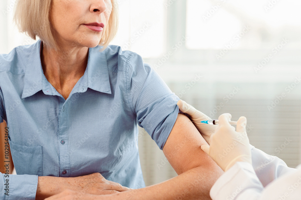 Healthcare Concept. Cropped image of unrecognizable nurse giving injection to mature woman, free space Healthcare Concept. Cropped image of unrecognizable nurse giving injection to mature woman, free space