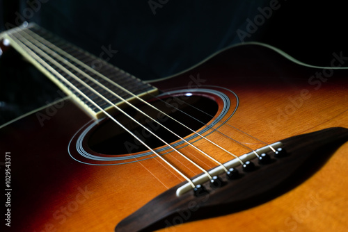 Acoustic guitar on black background, sunbrust body acoustic guitar parts close up,  plucked instrument, shallow depth of field part of a acoustic guitar, guitar chords, playing music