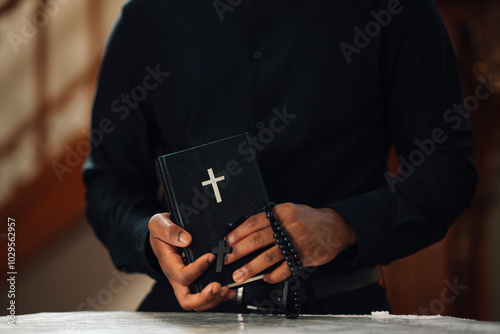 Priest holding holy bible and rosary beads
