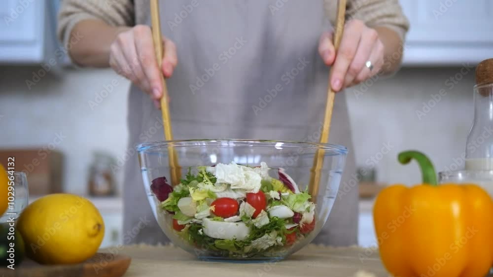 Housewife mixes salad from fresh vegetables. Vegetables fill large bowl. Skillful hands distribute vegetables and greens. Preparation healthy salad emphasizing juiciness and health benefits vegetables Housewife mixes salad from fresh vegetables. Vegetables fill large bowl. Skillful hands distribute vegetables and greens. Preparation healthy salad emphasizing juiciness and health benefits vegetables