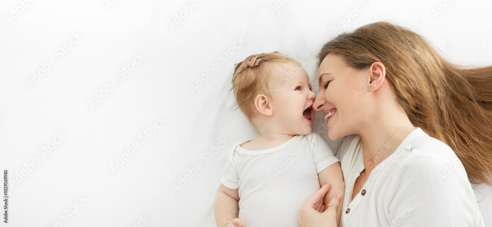Lovely time with kid. Happy young mother bonding with her cute baby girl, lying on bed together, top view, panorama with free space Lovely time with kid. Happy young mother bonding with her cute baby girl, lying on bed together, top view, panorama with free space
