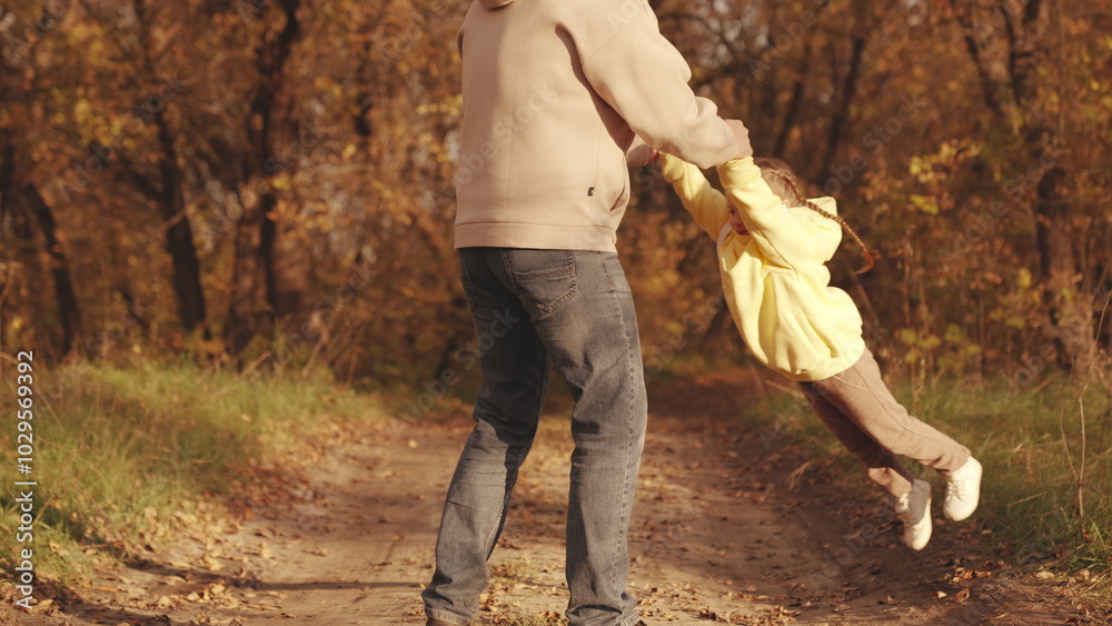 Obraz premium happy family park. father circling little child daughter his arms autumn park. kid with dad dreams becoming pilot. concept childhood dream flight. child spinning with his father forest autumn leaves