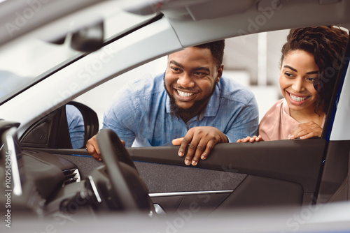 Choosing Auto. Black Couple Looking At Car Interior Buying Family Automobile In Dealership Showroom. Selective Focus, Free Space